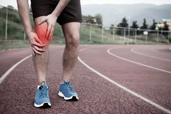 Colour photo of man on tracks holding his knee as if in pain