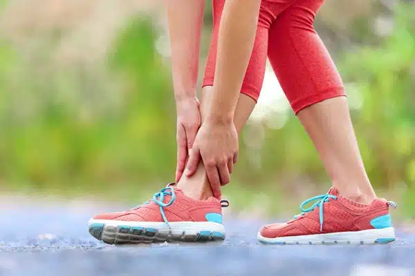 Ankle and foot pain illustrated by woman holding her ankle